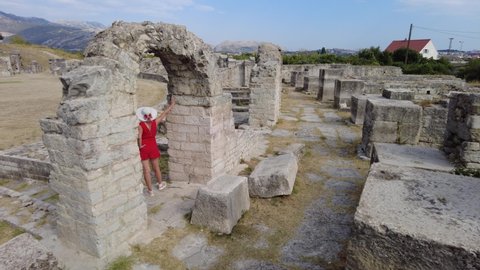 Tourist lady walking in the Salona ruins of the Ancient Roman Amphitheatre of Dalmatia in Croatia. Historic Roman coliseum ruins in Flavian architectural style.