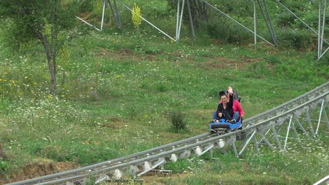 Bansko, Bulgaria - 20 Aug, 2021: Tourist enjoy downhill roller coaster trolley passing through tropical forest