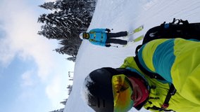 couple skiing by mountains slope shooting selfie vertical video