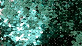 Texture of green shiny sequins. Fashionable bright fabric with sequins.