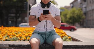 Man choose playlist for listening to music in a city, cropped video