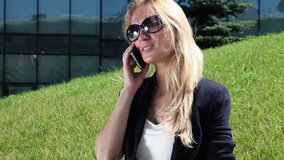Young woman talking on cellular phone on the background of office building
