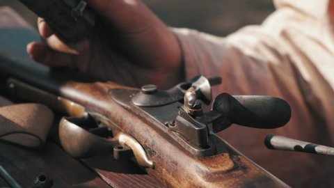 a man repairs an antique musket, a man repairs a musket with a screwdriver