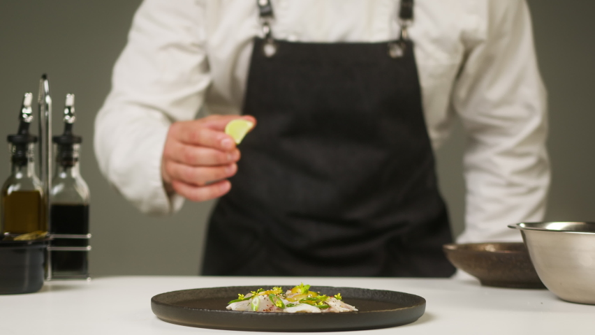 Professional Chef squeezing lime juice on peruvian ceviche on cutting board close-up. Man cooking seafood dishes using citrus fruits. Traditional Peruvian cuisine. 