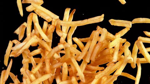 Super slow motion of flying french fries on black background. Speed ramp effect. Filmed on high speed cinema camera, 1000 fps.