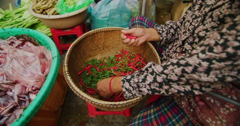 Slow Motion-a woman picking red chillies at an outdoor market where you can ride your motorcycle through. Red Helium camera-8k resolution-vintage Zeiss lenses in Phnom Penh, Cambodia.
