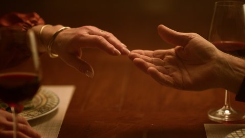 Senior love couple hands touching each other in restaurant. Closeup rich grandparents enjoying retirement life together. Unknown tender old husband wife romantic dinner home. Care family relationship