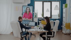 Colleagues talking to woman on video call for business meeting in boardroom. Workmates using television to call employee on online conference for project planning and strategy briefing