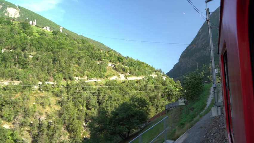 Panoramic view from the Swiss train window of the Alpine mountains and gorges.