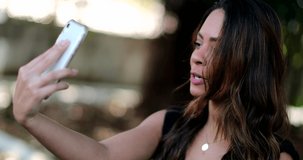 Woman holding cellphone outside speaking in front of smartphone camera webcam