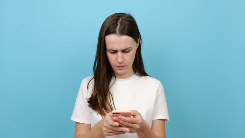 Young caucasian woman holding smartphone feel eye strain fatigue, brunette girl suffer from pain in dry irritated eyes, bad blurry vision eyesight problem, isolated over blue color background studio | Shutterstock HD Video #1080013628