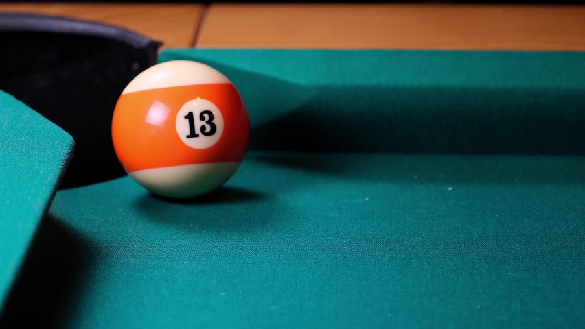 A billiard ball with an orange stripe number 13 is pocketed. Slow motion. Selective focus. | Shutterstock HD Video #1080014009