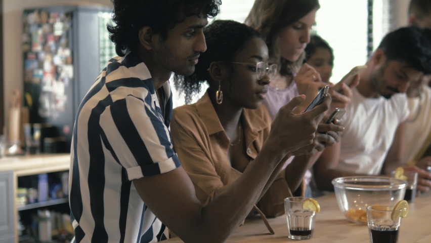 Big group of Young diverse multiracial people sitting together and looking at their phones - Social media concept and addiction, millennials lifestyle