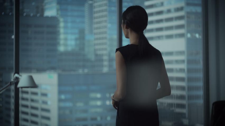 Successful Businesswoman in Stylish Dress Looking out of the Window at Big City in Downtown Area. Confident Female CEO Working on Financial Projects. Manager at Work Planning Marketing Campaign. | Shutterstock HD Video #1080017261