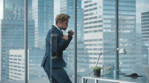 Excited Handsome Businessman Jumps Around the Office and Punches Air in Success. Young CEO Happy After Board Meeting. Manager in a Suit Wins an Investment Deal, Purchase Profitable Business Company.