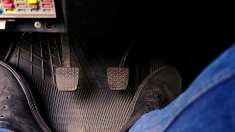 Male feet pedaling in a dirty old car.