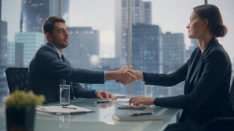 Female and Male Business Partners Sign Successful Deal Documents and Shake Hands in Meeting Room Office. Corporate CEO and Investment Manager Handshake on a Lucrative Financial Opportunity.