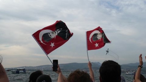 Izmir, Turkey - September 9, 2021: Planes flying on sky on the liberty day of Izmir for a demonstration. People waving Turkish flags in the frame. Slow motion footage.