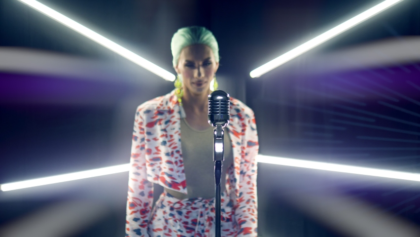 portrait male travesty artist singing into a microphone on stage in the light of safit.