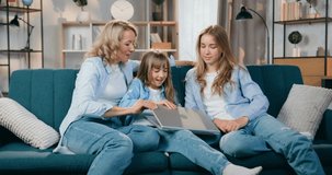 Family concept where beautiful emotional happy smiling mother and her two daughters have pleasant video chat with relatives on computer at home ,front view