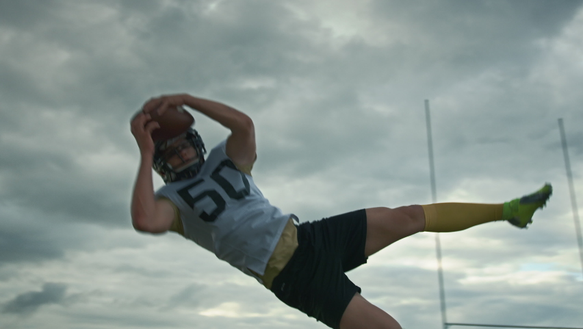 American Football Player Catches Ball Pass in Flight and Scores Championship Winning Points. Cinematic Shot of Dramatic Moment in a League Tournament, Successful Athlete Bringing Victory to the Team