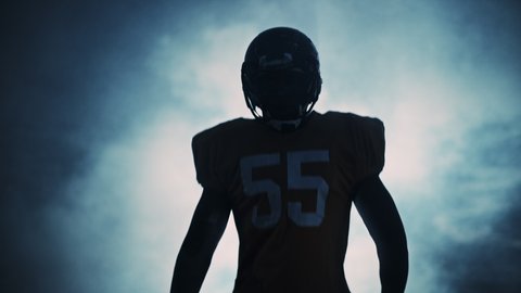 American Football Player Warrior Warming up. Hero Athlete Getting Berserk and Ready to Win. Determination, Skill, Power, Energy. Dramatic Light and Fog. Cinematic Slow Motion of Sportsman Silhouette