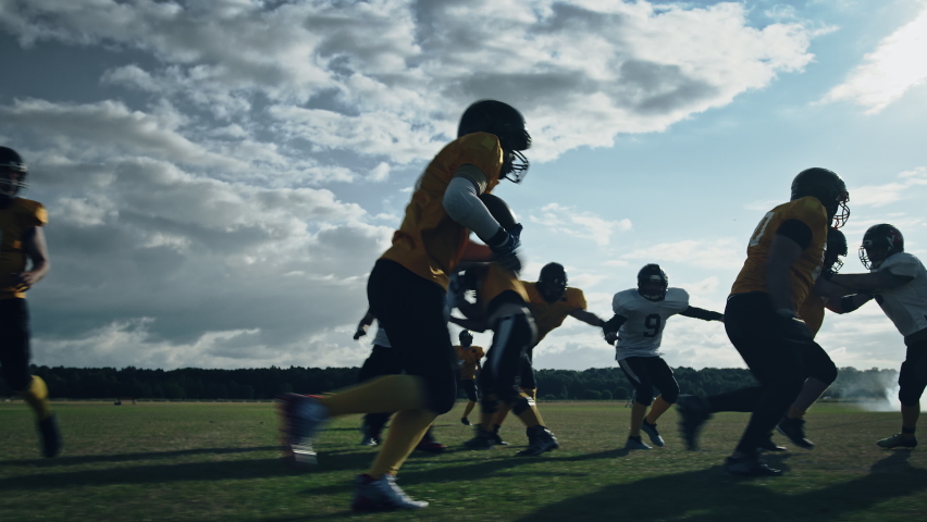 American Football Field Two Teams Compete: Players Pass and Run Attacking to Score Touchdown Points. Athletes Brutally Compete for the Ball, Tackle Each other. Cinematic Slow Motion with Dramatic Shot
