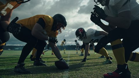 American Football Field: Two Professional Teams Clash, Attacking to Score Touchdown Points. Athletes Brutally Compete for the Ball, Tackle Each other. Dramatic Slow Motion with Immersive Cinematic