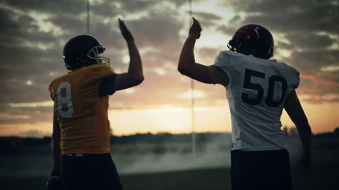 American Football Game Start Teams Ready: Two Professional Players Walk on Field Determined to Win the Match. Competitive Friends do Celebration High-Five. Immersive Handheld Following Shot