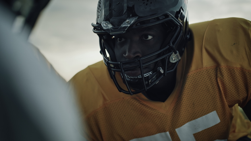 American Football Game Start Teams Ready: Close-up Portrait of Professional Player, Aggressive Face-off. Competitive Warrior Full of Brutal Energy, Power, Skill. Dramatic Stare. Cinematic Shot
