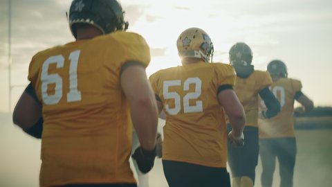 American Football Game Start Teams Ready: Two Professional Teams Walk on Field Ready to Fight for Champion Title. Competition Full of Brutal Energy, Power, Skill. Immersive Handheld Following Shot