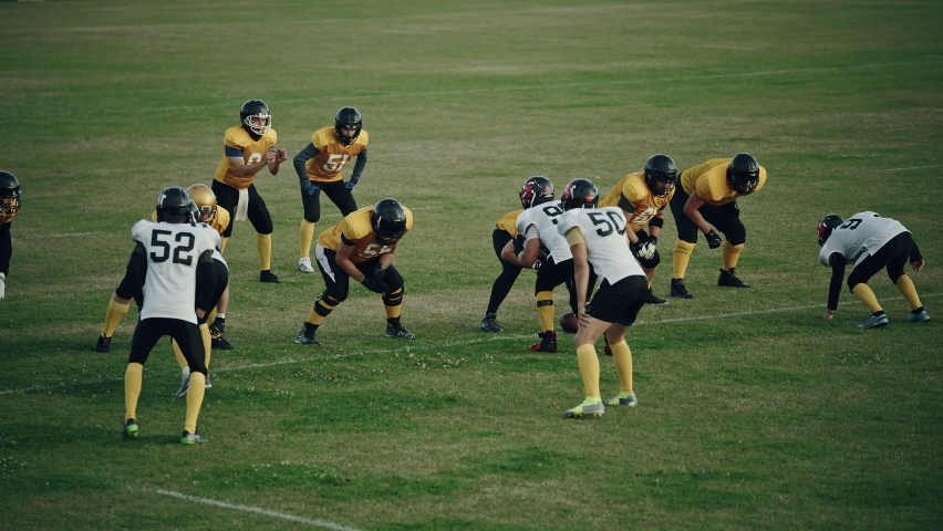 American Football Field Two Teams Compete: Successful Player Jumping Over Defense Running to Score Touchdown Points. Professional Athletes Compete for the Ball, Tackle, Fight for Victory. Wide Shot Royalty-Free Stock Footage #1080022313
