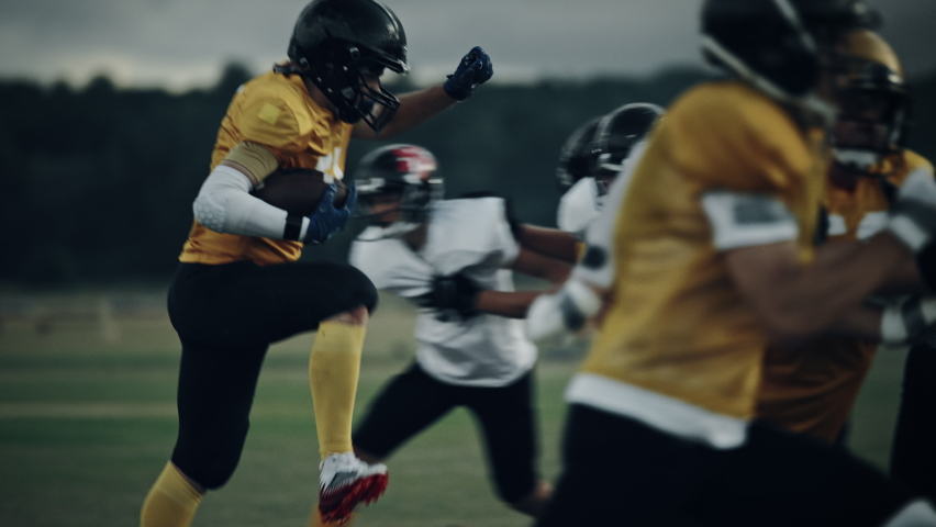 American Football Field Two Teams Compete: Successful Player Jumping Over Defense Running to Score Touchdown Points. Professional Athletes Compete for the Ball, Tackle, Fight for Championship Victory