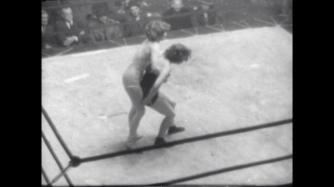1940s: Lady wrestler slams opponent to mat and pins her. Referee counts the pin and points to winner. Sign placard. Four wrestlers brawl in ring.