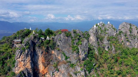 White pagoda and stupa on top of mountain cliff in woodland called Wat Phra Bat Pupha Daeng temple, Chae Home, Lampang province, Thailand.