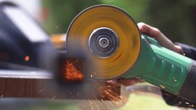 A zoomed in video of bright orange sparks formed through welding iron being used by a woman worker, spreading in the surroundings, dispersing in air