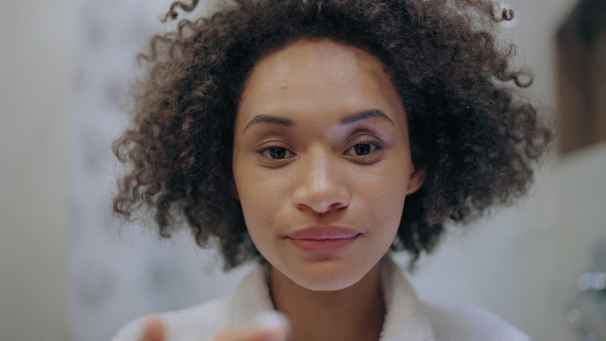 Happy young female applying moisturizing cream on face, self-care routine, age | Shutterstock HD Video #1080029987