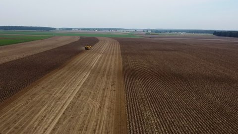 Tractor and harvester on an agricultural field in Poland. Drone shot. Aerial view, top view from above. Cinematic.