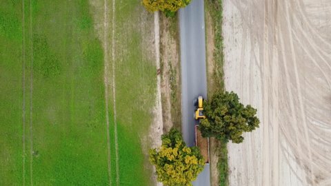 Tractor driving with potatoes on a small road in Poland. Drone shot. Aerial view, top view from above. Cinematic.