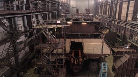 Old rust renewable crab ship hanging crane hook and high scaffolds in spacious dry dock of industrial complex