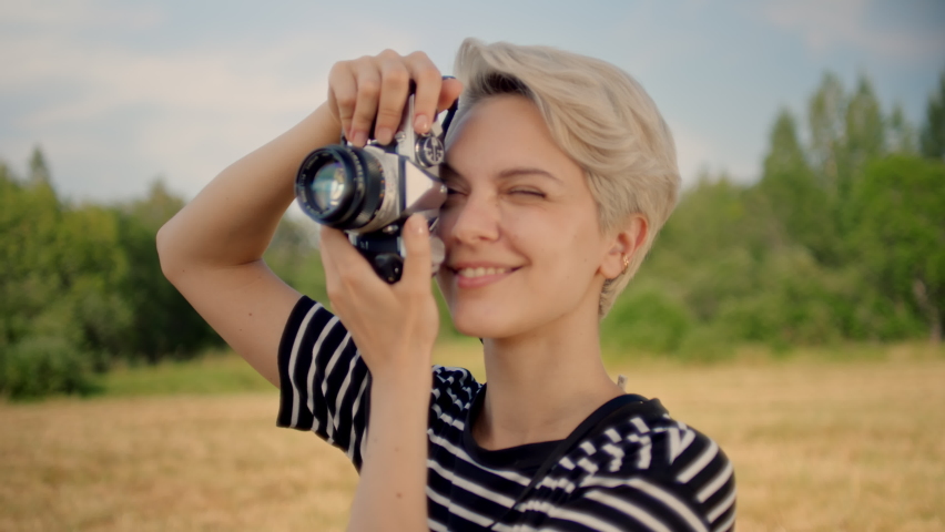 Professional female photographer gives directions to model behind lens. Happy occupation empowered and independent woman work for commercial magazine or agency.Young woman make photos on analog camera