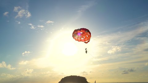 Tourists parasailing slow motion flying on sky during sunset mountain background.Activity sports beach relax weekends.Summer vacation and holiday.Famous landmark to travel destination trips. camera 4K