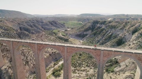 Caravaca de la Cruz , Murcia , Spain - 09 30 2021: People Cross At Old Viaduct In The Valley On A Sunny Summer Day. - aerial