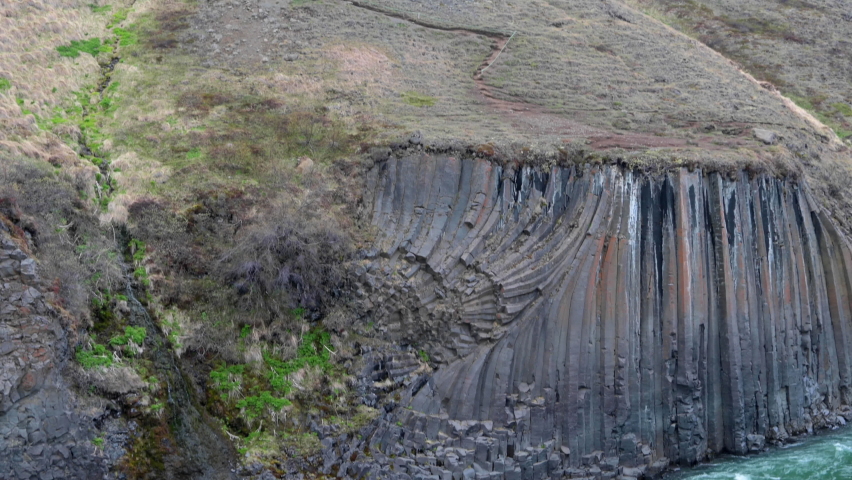 Green water river flowing in a canyon with high basalt columns