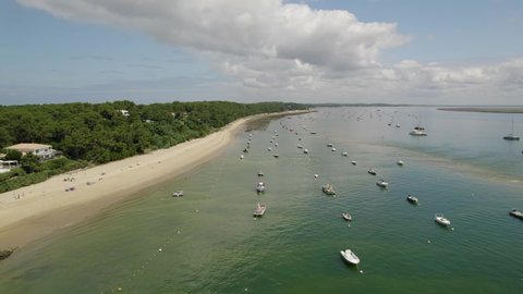 Beachside oyster farm in Le Canon at Cap Ferret peninsula in France with fishing boats right, Aerial flyover shot