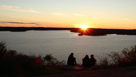 Beautiful sunset over the Swedish lake Malaren. People enjoying the last sun beams. Sunny dramatic and amazing horizon. Nice sky in September. Rear view.  Stockholm, Sweden, Euro