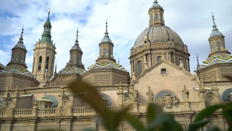 Lateral movement with the leaves of a flowerpot and the cathedral-basilica of Nuestra Señora del Pilar in Zaragoza in the background. Zaragoza, City. Spain