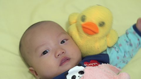 Cute skinhead baby with old yellow plush duck look at camera
