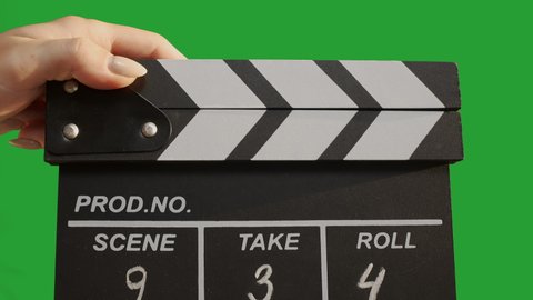 Human hands are using a clapperboard isolated on green screen. Beginning of scene in film or television production. Concept of cinematography or movie and film crew or video. Chroma key.