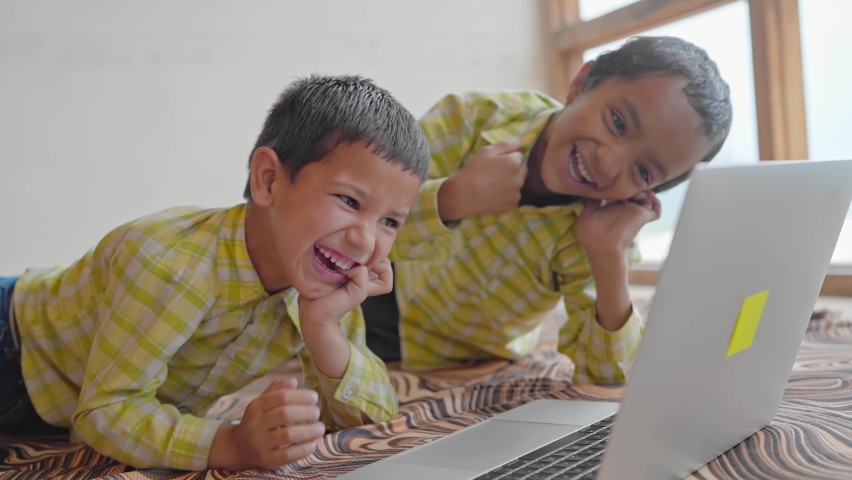 A shot of two Indian Asian pre school or primary male children or kids wearing uniforms is watching a funny video on a laptop and laughing together in an indoor setup. learning and education concept Royalty-Free Stock Footage #1080062672